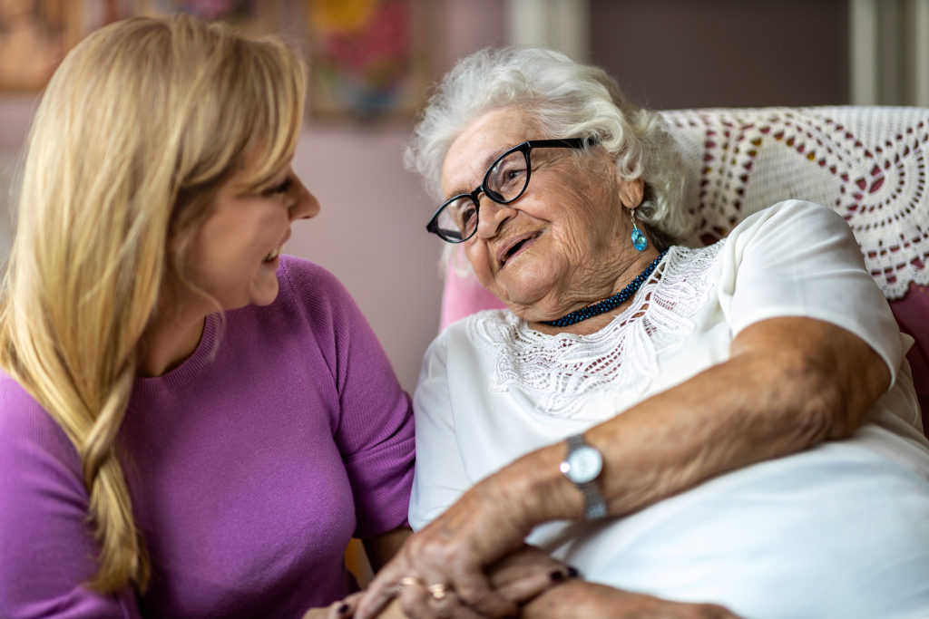 Young woman spending time with her elderly grandmother at home. Learn about life for people with Alzheimer’s disease to inform your caregiving decisions.