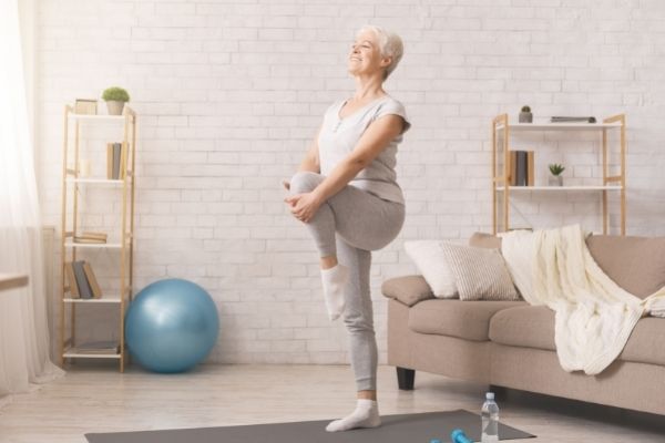 A woman practices balance exercises for seniors in her home.