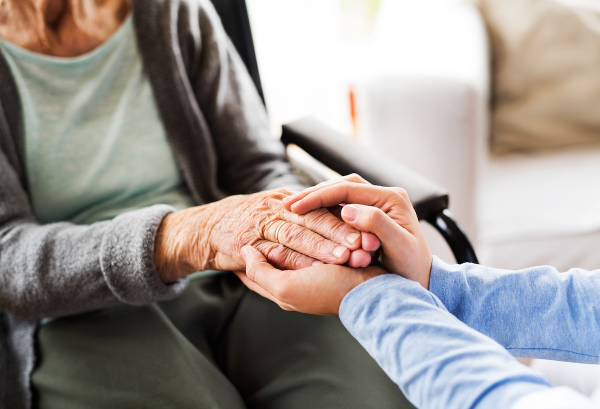 Woman and elderly patient holding hands