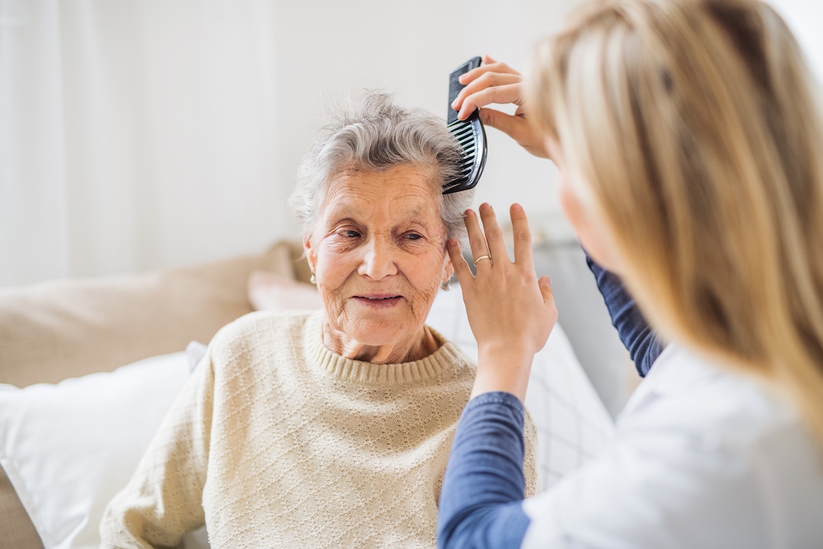 Healthcare worker brushing an elderly woman's hair
