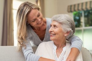 a senior woman and her adult daughter embracing and smiling at one another