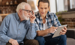 A father and son review research on a tablet about how to pay for in-home care.