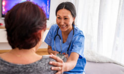 A smiling aide performs a blood pressure check as part of in-home care for a senior with dementia.