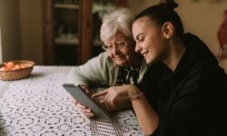A grandmother and granddaughter do online research on how to get 24-hour care for the elderly at home.