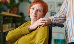 an elderly woman holds the hand of her in-home dementia caregiver