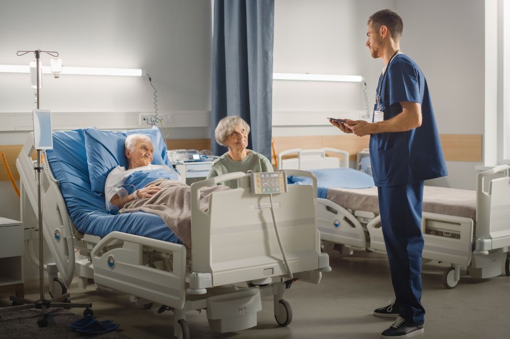 A doctor discussing in-home after-surgery care with an elderly man who just had a knee replacement while his wife listens.