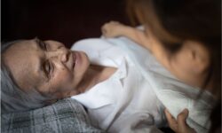 A professional caregiver helps an elderly woman to bed as part of overnight care for seniors services provided by an agency.