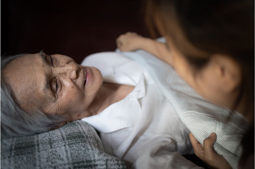 A professional caregiver helps an elderly woman to bed as part of overnight care for seniors services provided by an agency.