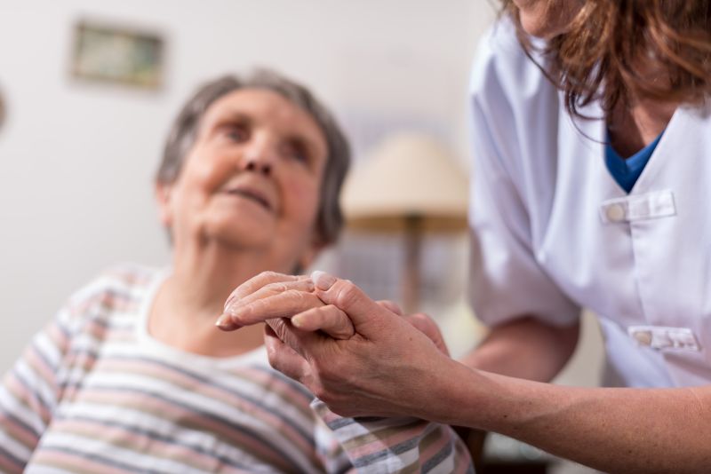 Healthcare worker supporting elderly woman