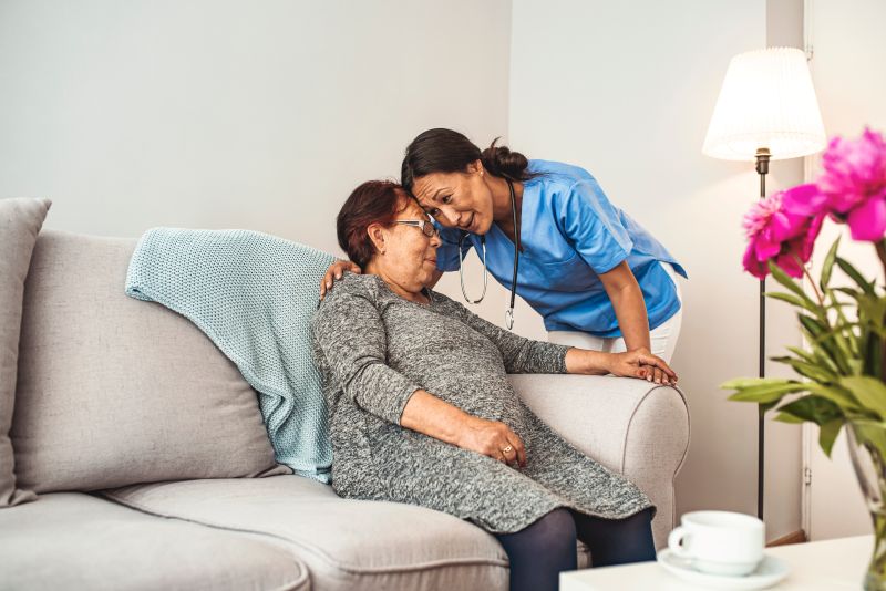Caregiver supporting elderly woman at home