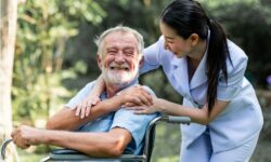 An elderly man getting assistance from his aide that he pays for using insurance that covers in-home care.