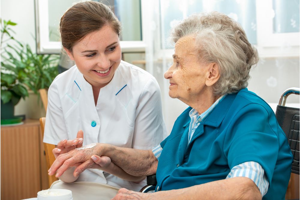 An elderly woman who arranged for in-home palliative care is assisted by an aide with hygiene care.