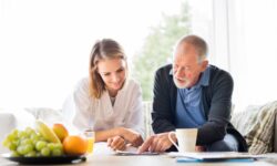 A caregiver reviews the daily routine with her elderly client over a cup of coffee.