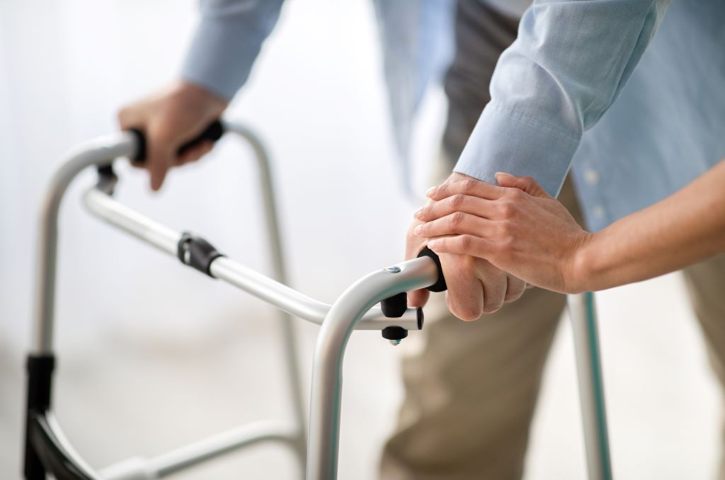  A caregiver helps her client with his walker following a stroke.
